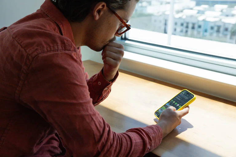 Chase Shelly reviewing Instagram performance on his phone by a window
